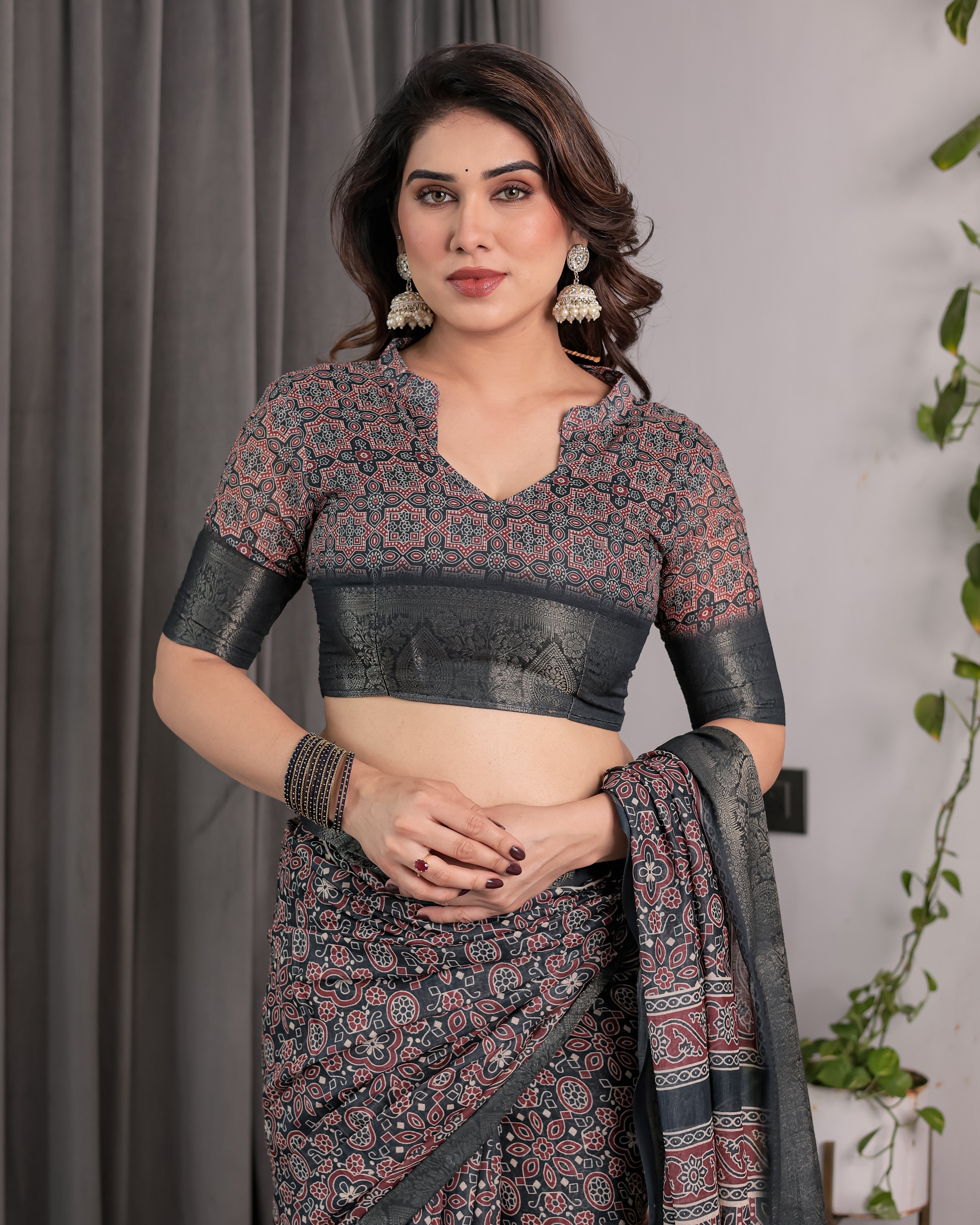 Woman wearing a traditional saree with a patterned blouse against a neutral background