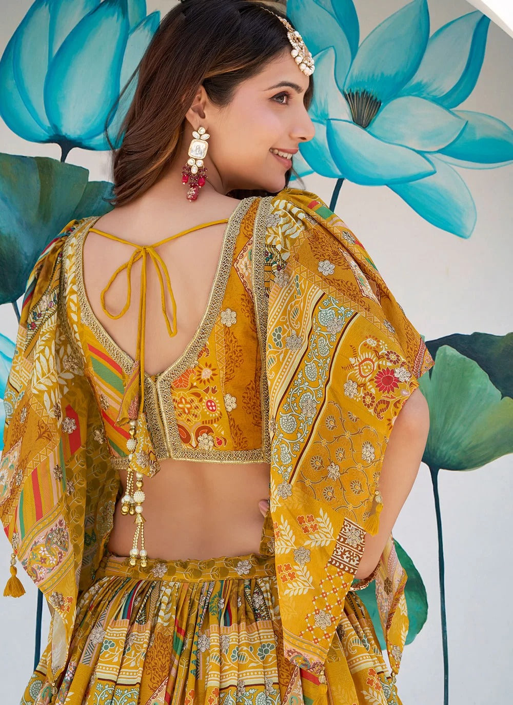 Woman in a yellow traditional outfit with floral patterns against a floral background