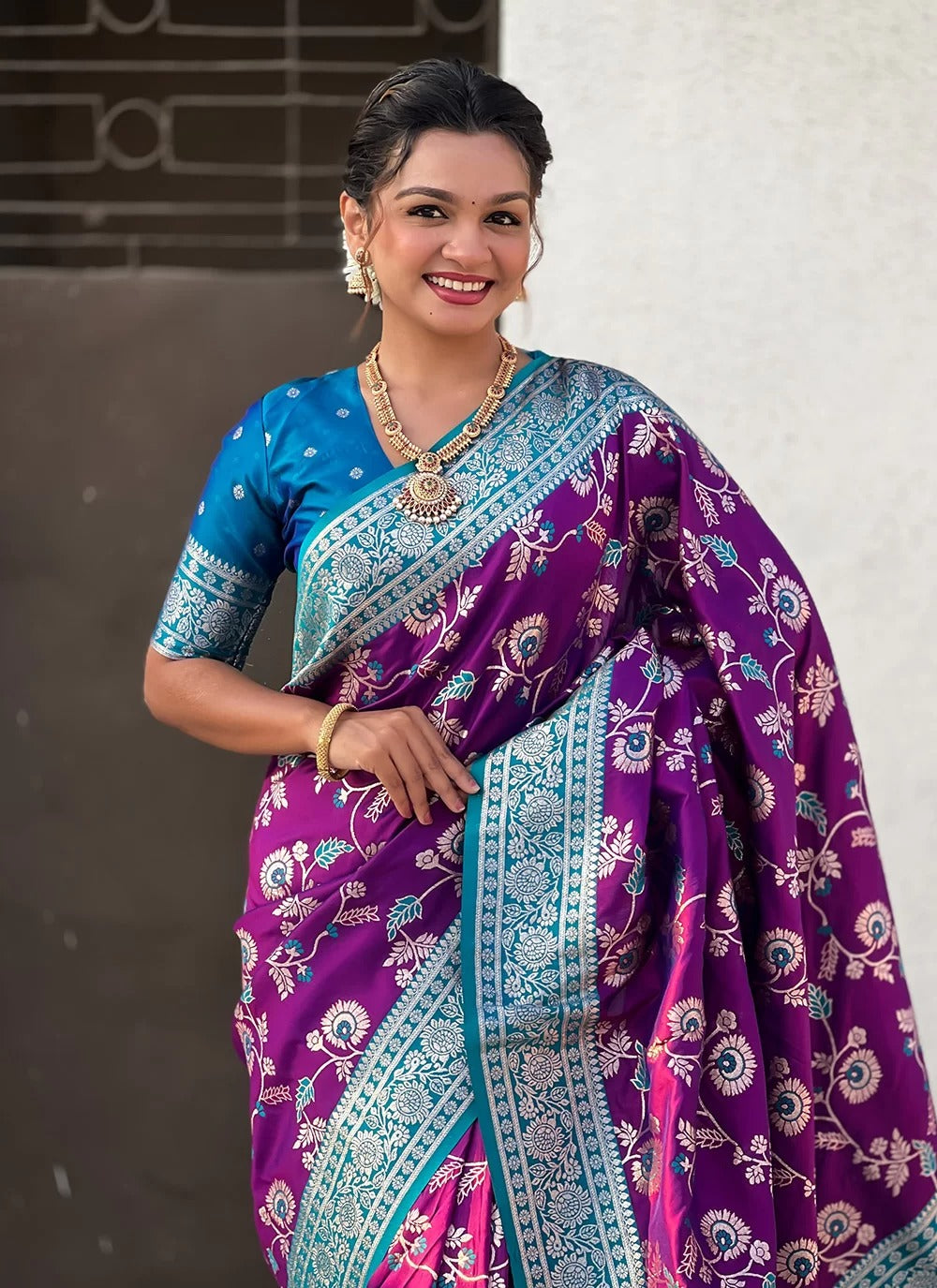 Woman wearing a purple and blue saree with a white background