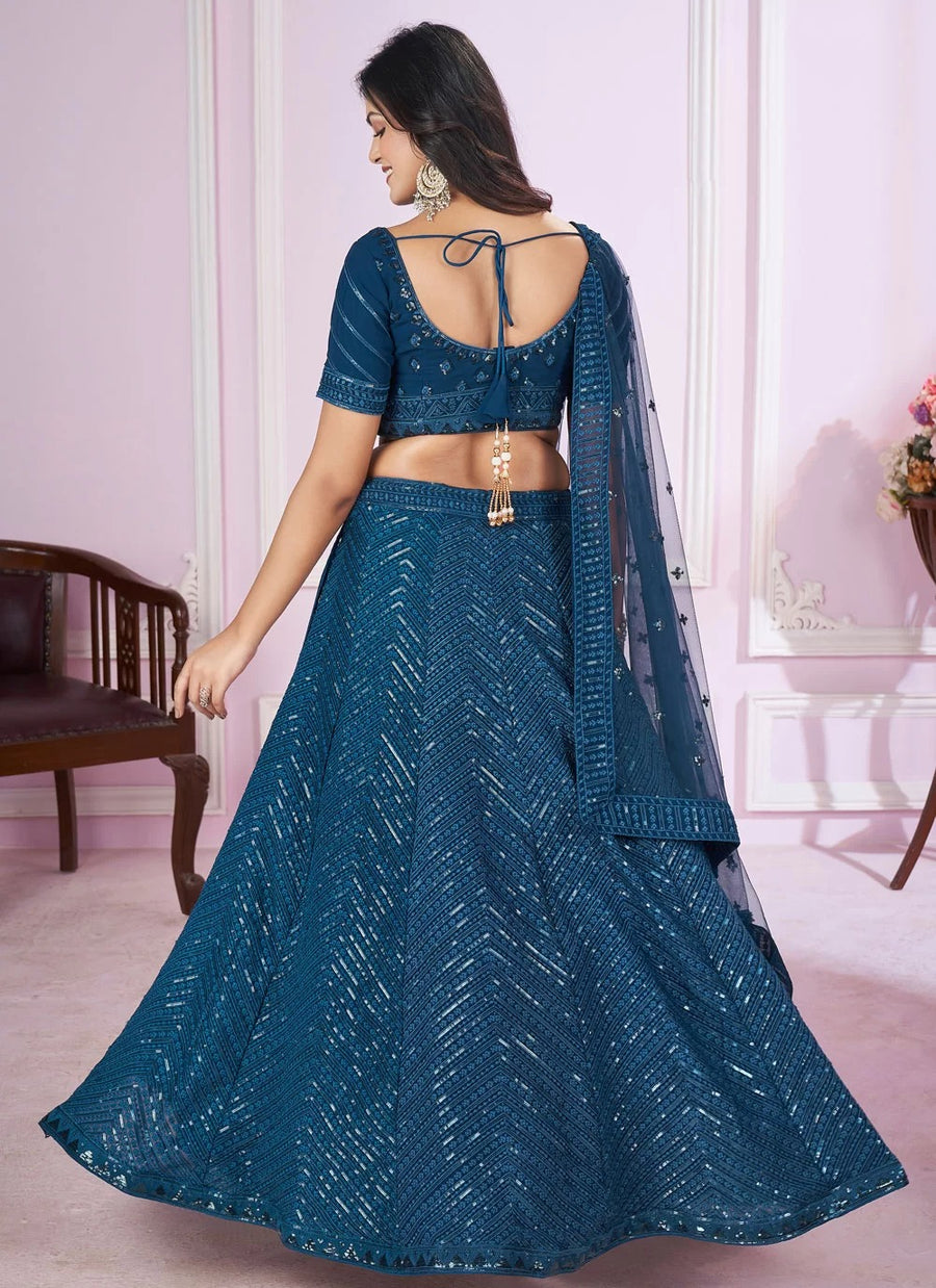 Woman wearing a blue traditional outfit with a matching dupatta in a room setting.
