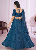Woman wearing a blue traditional outfit with a matching dupatta in a room setting.