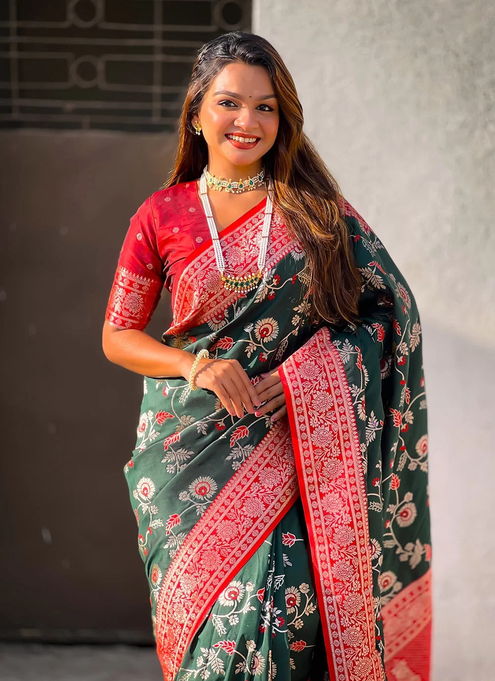 Woman wearing a traditional saree with a red and green pattern.