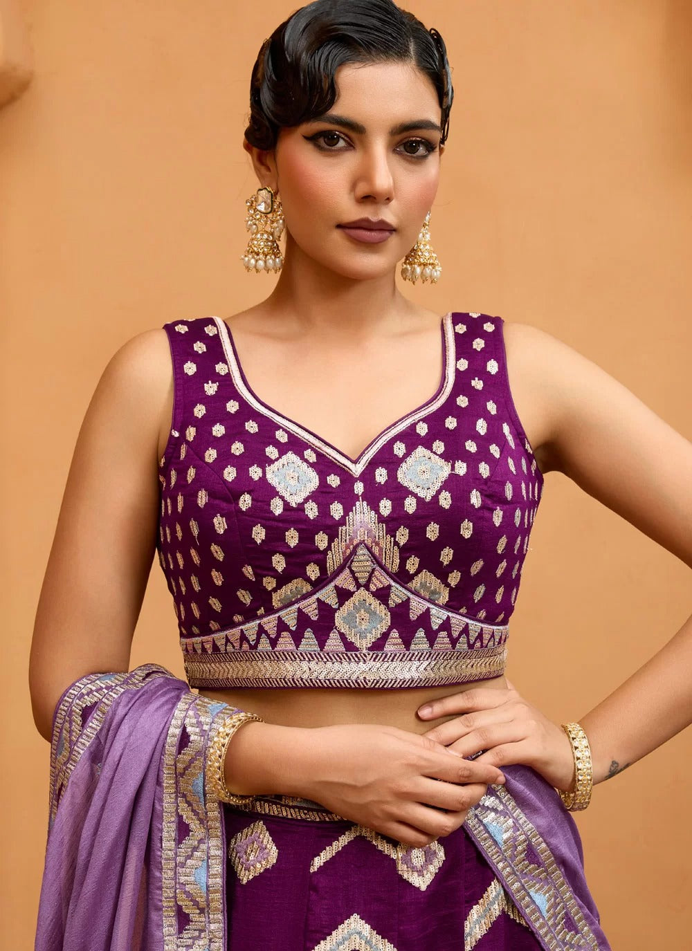 Woman wearing a purple traditional outfit with gold accents against a beige background