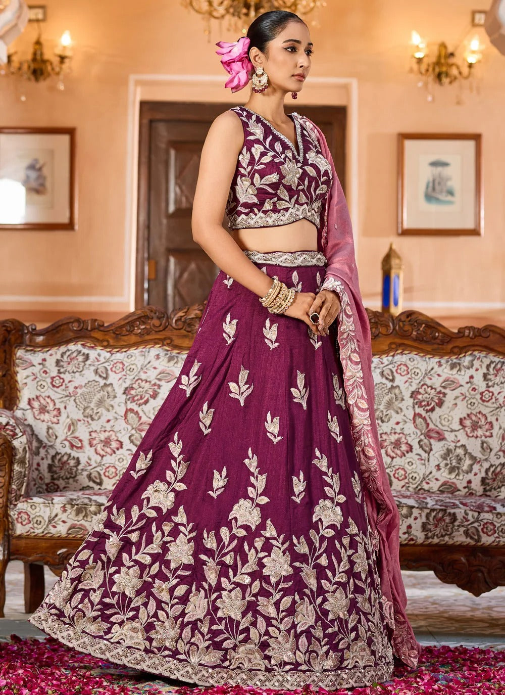 Woman in a purple embroidered traditional outfit standing in an elegant room.