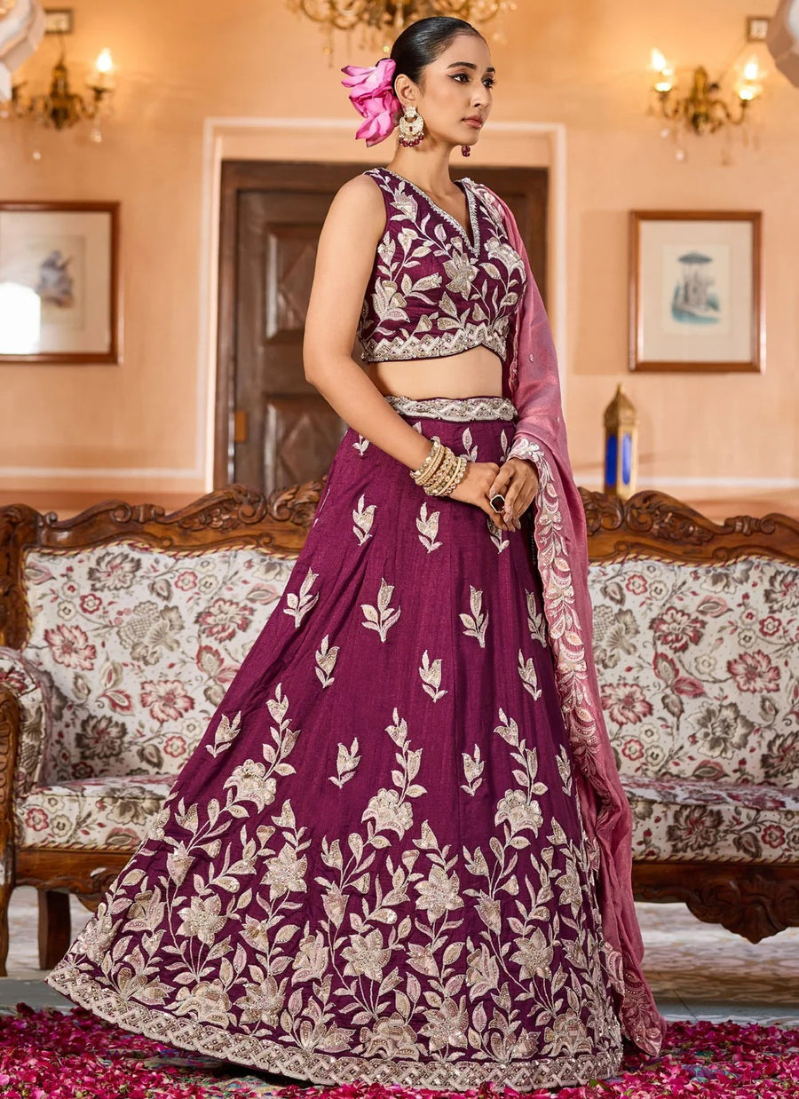Woman in a purple embroidered traditional outfit standing in an elegant room.
