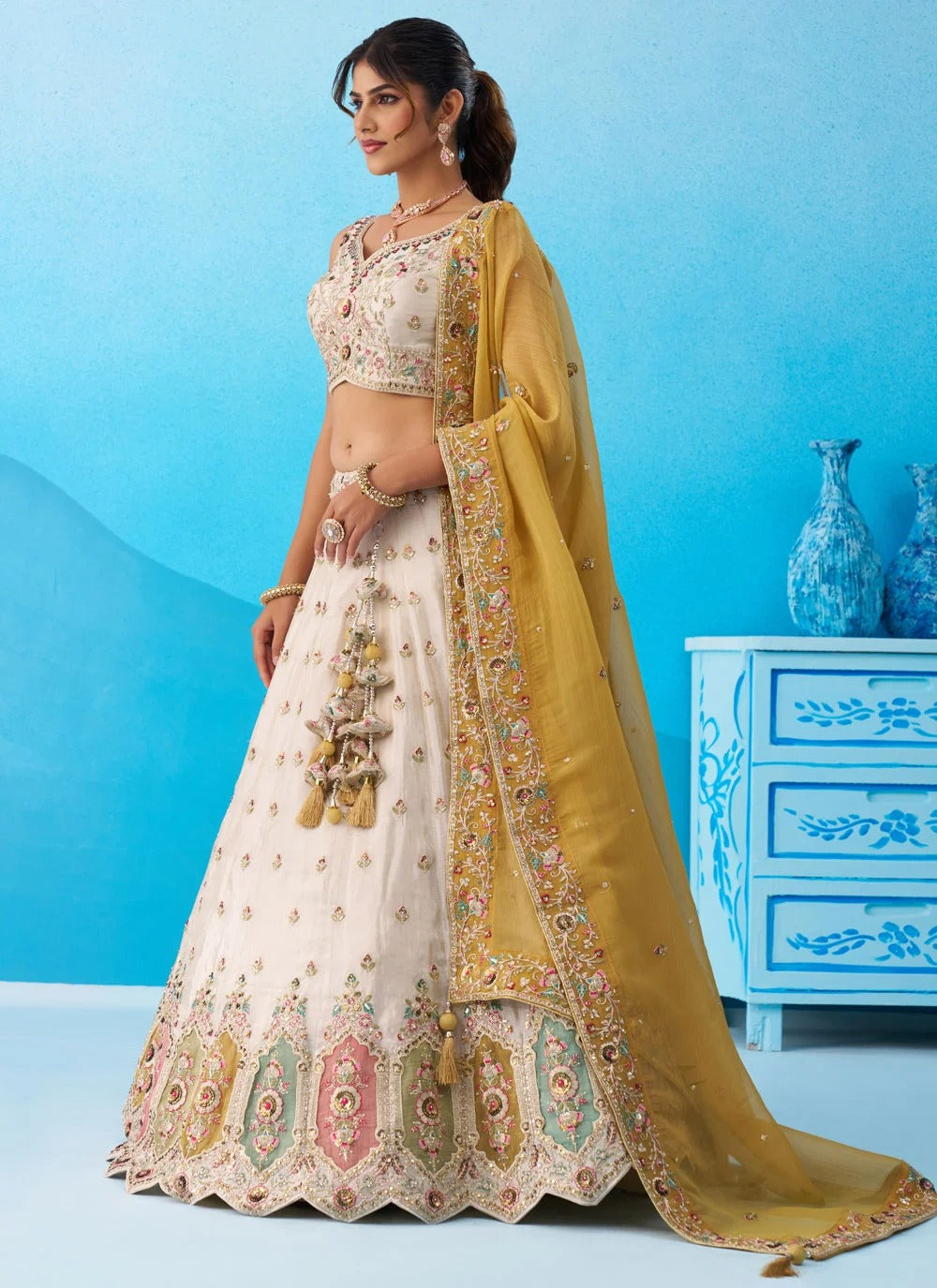 Cream tissue patch work lehenga featuring heavy sequins embroidery, multicolor patch work and a mustard tissue dupatta with colourful cutwork border.