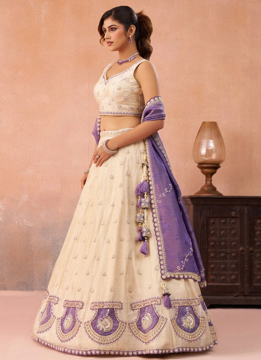 Designer wedding lehenga in premium cream jacquard featuring peacock patch work, heavy bead and silver sequins embroidery with a contrasting purple jacquard dupatta.