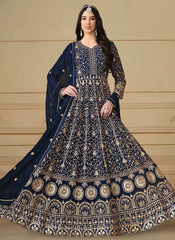 Woman wearing a navy blue and gold embroidered traditional outfit with a beige background