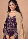 Woman wearing a purple dress with floral patterns and a beige dupatta on a beige background