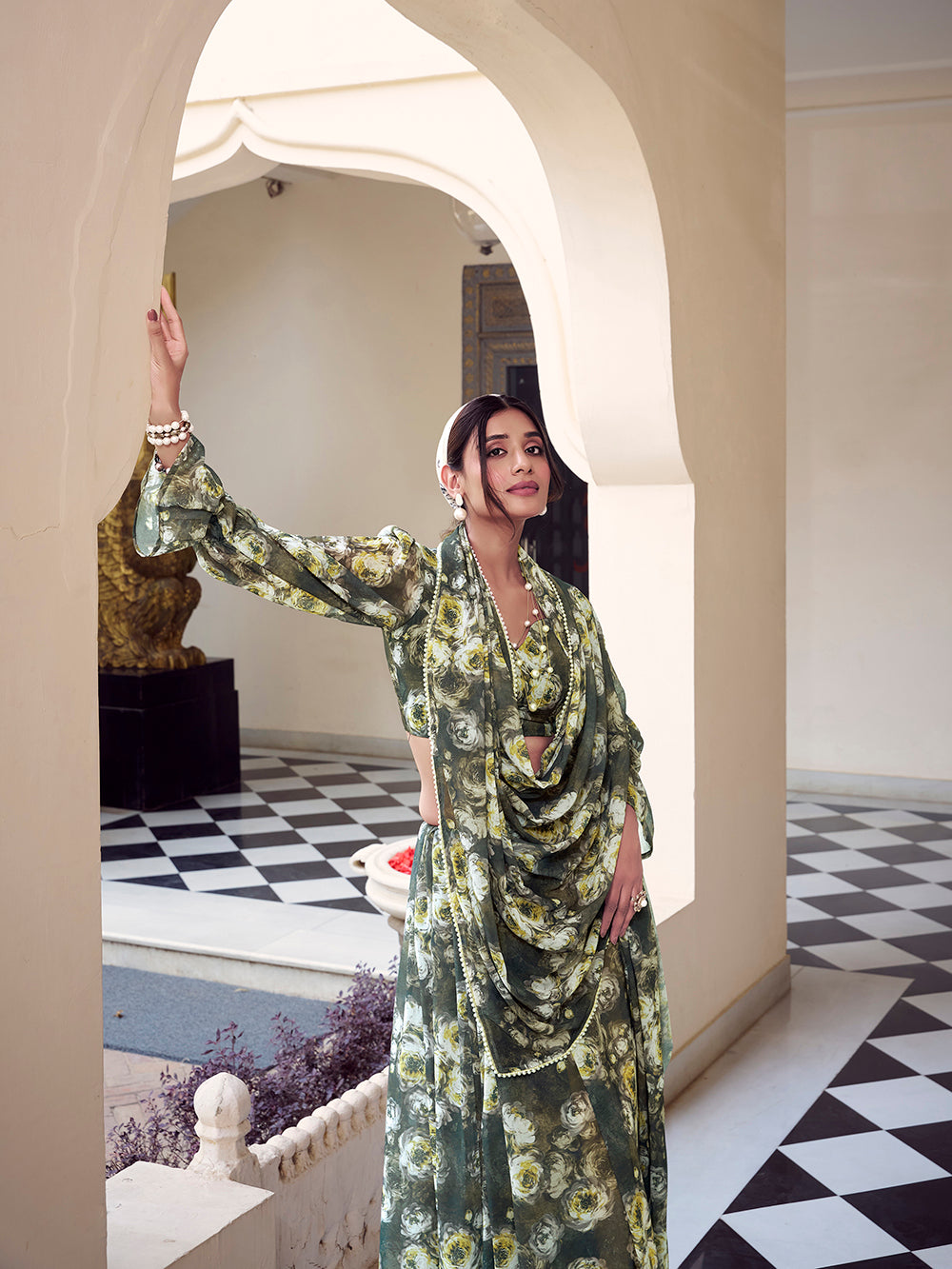 Woman in a floral dress standing in an elegant interior setting with checkered floor and archway.