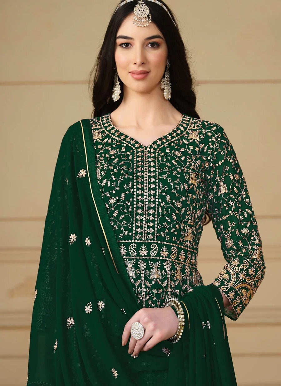 Woman wearing a green embroidered traditional outfit with a beige background