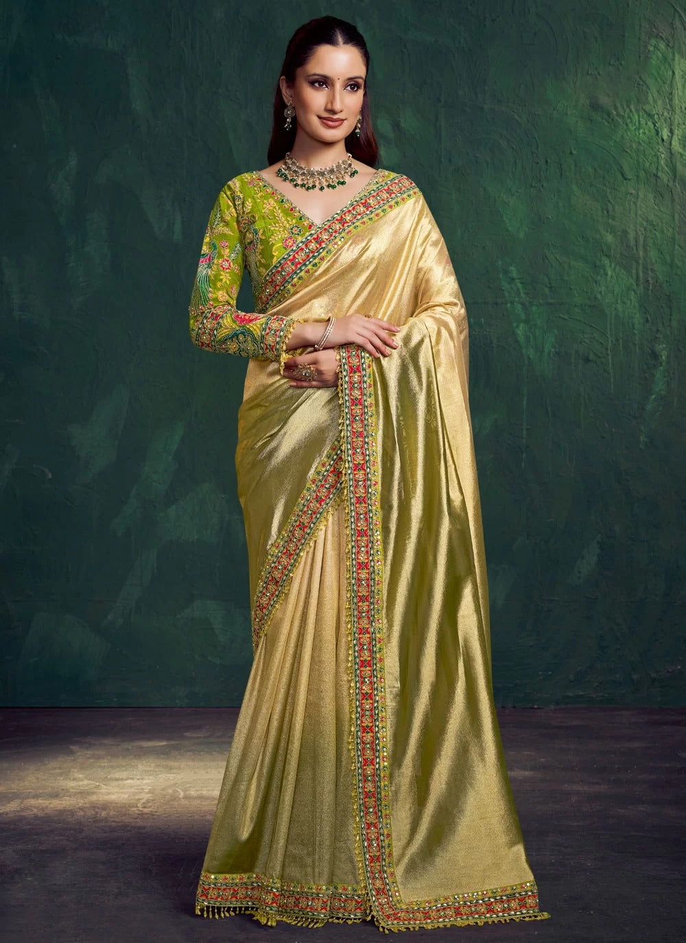 Woman wearing a traditional green and gold saree with a dark background