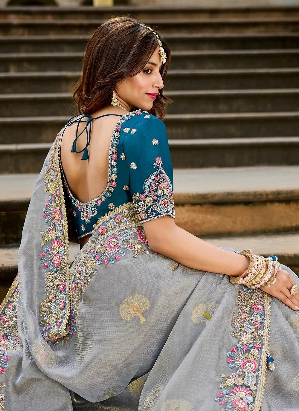 Woman in traditional embroidered outfit sitting on steps