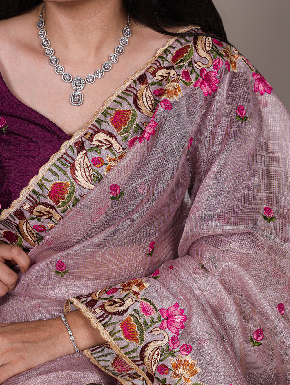 Close-up of a saree with intricate embroidery and a necklace.
