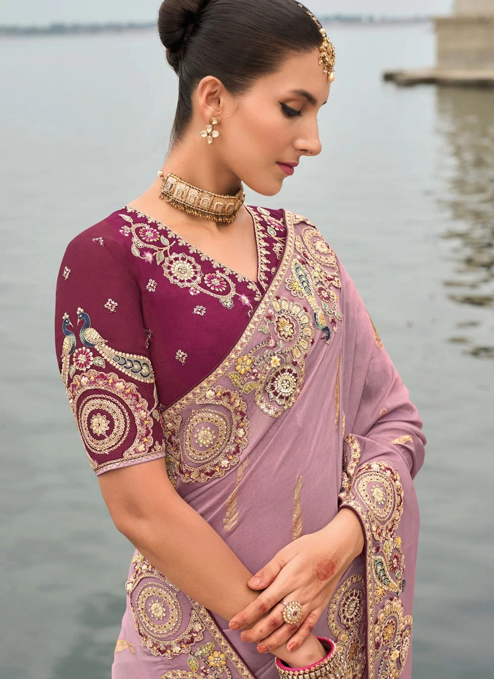 Woman wearing a traditional embroidered saree by a body of water