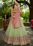 Woman in a traditional green and pink embroidered outfit standing outdoors.