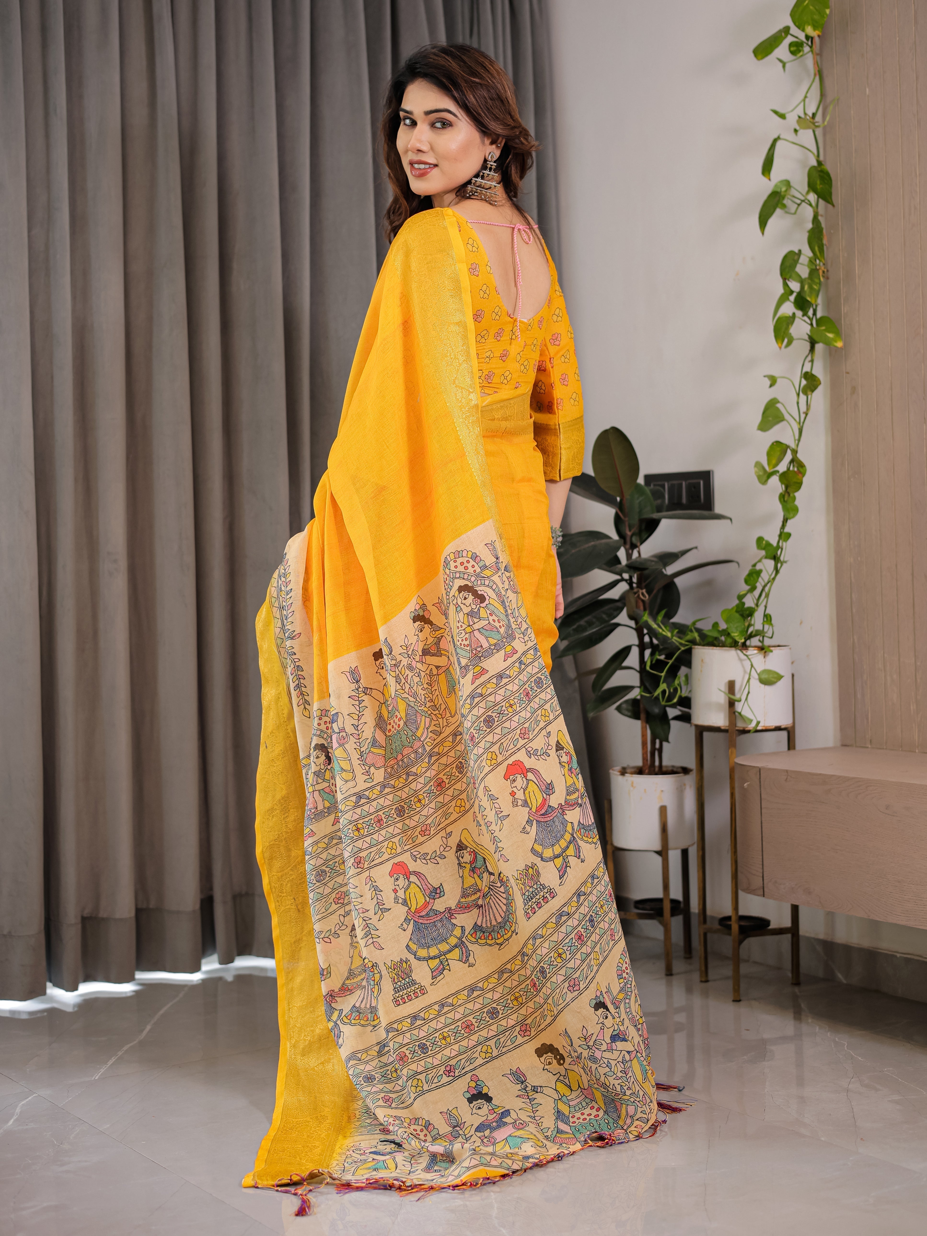 Woman wearing a yellow saree with intricate patterns indoors.
