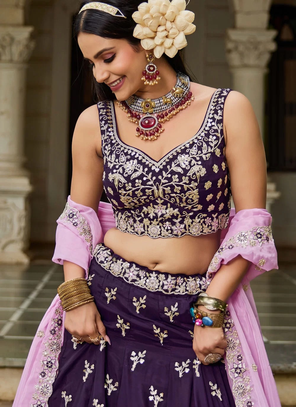 Woman in traditional Indian attire with jewelry and a floral headpiece.