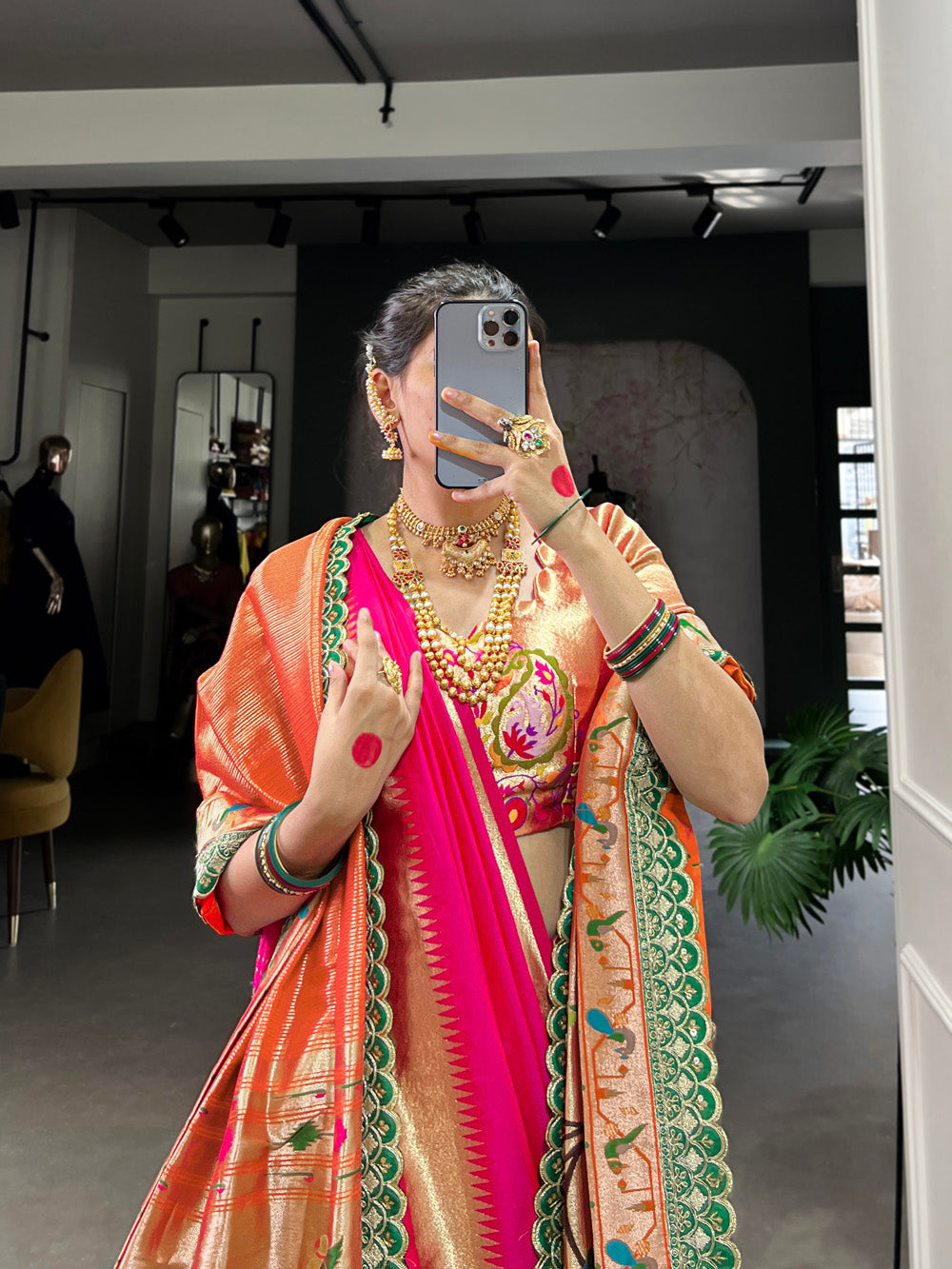 Person wearing a colorful saree with jewelry indoors.