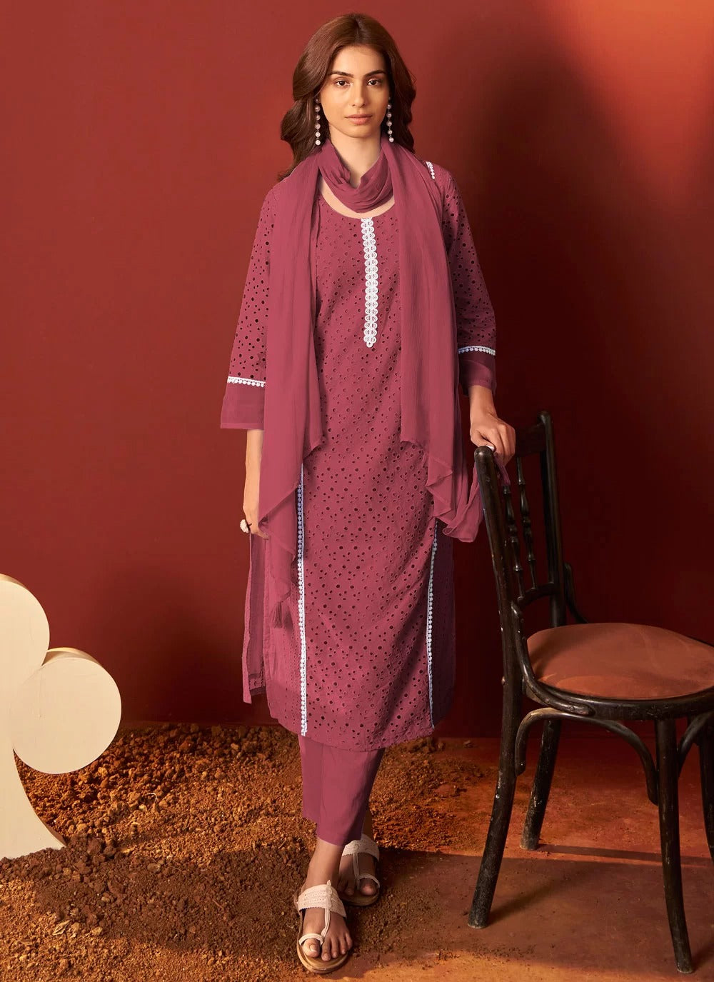 Woman in a maroon traditional outfit with a matching dupatta against a red background