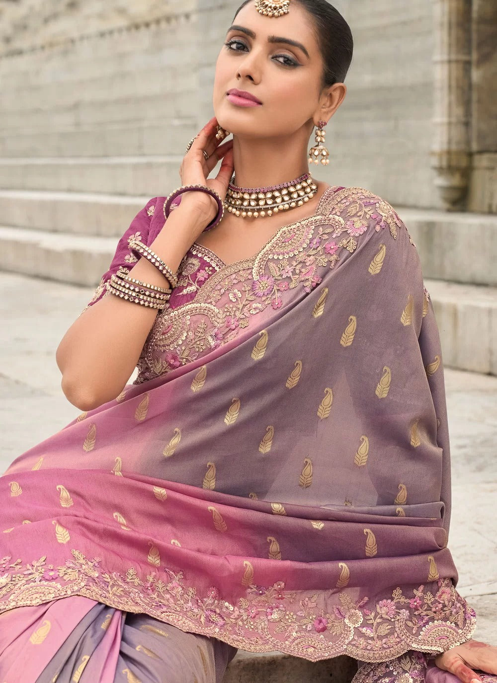 Woman wearing a traditional saree with intricate designs outdoors.
