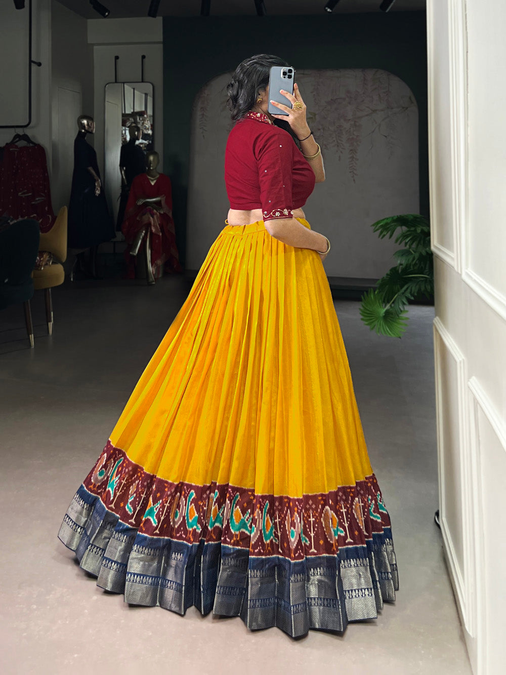 Person wearing a red blouse and yellow pleated skirt with a patterned bottom in a room.