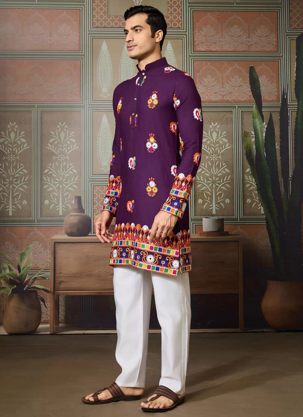Man wearing a colorful traditional outfit with a patterned background