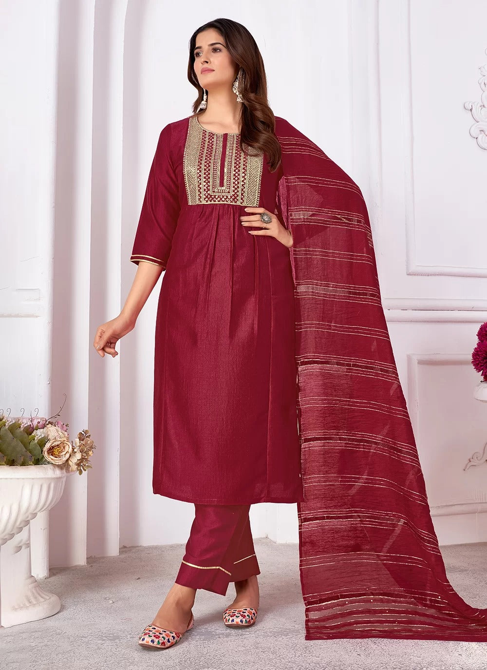 Woman wearing a maroon traditional outfit with a matching dupatta in a well-lit room.