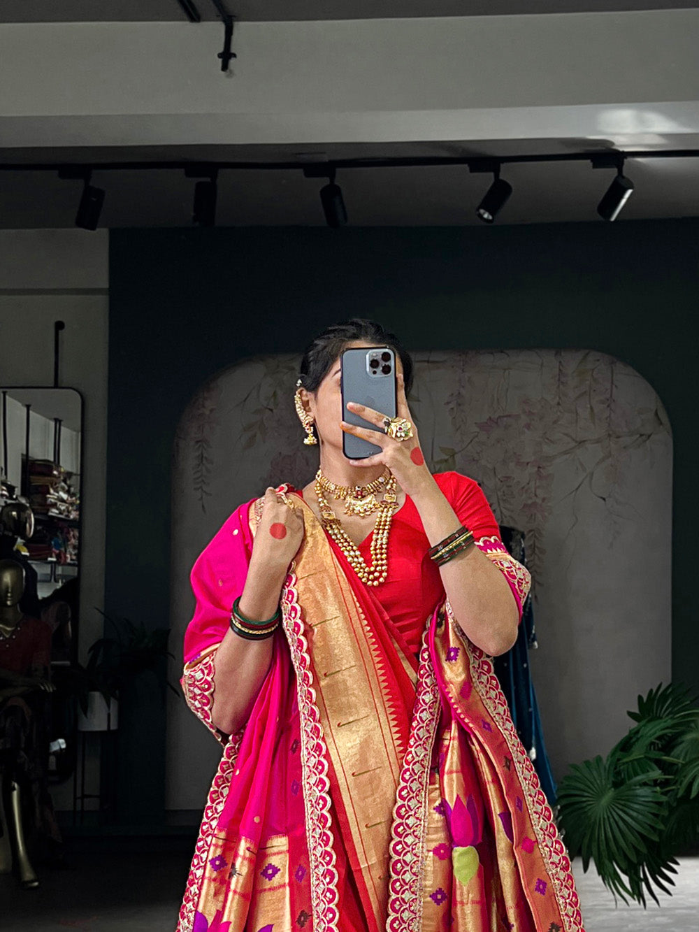 Person wearing a red saree with gold border in a room setting.