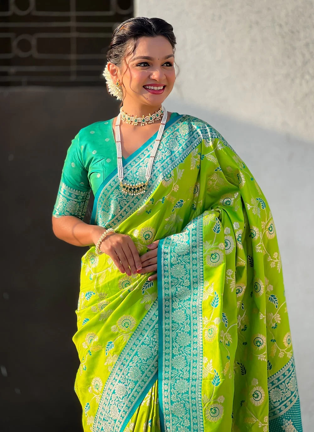 Woman wearing a green and blue saree with a white background