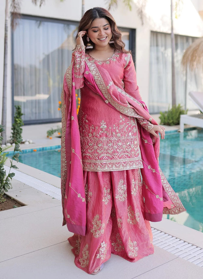Woman in a pink traditional outfit standing by a poolside.