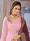 Woman wearing a pink traditional outfit with a maroon dupatta in an indoor setting