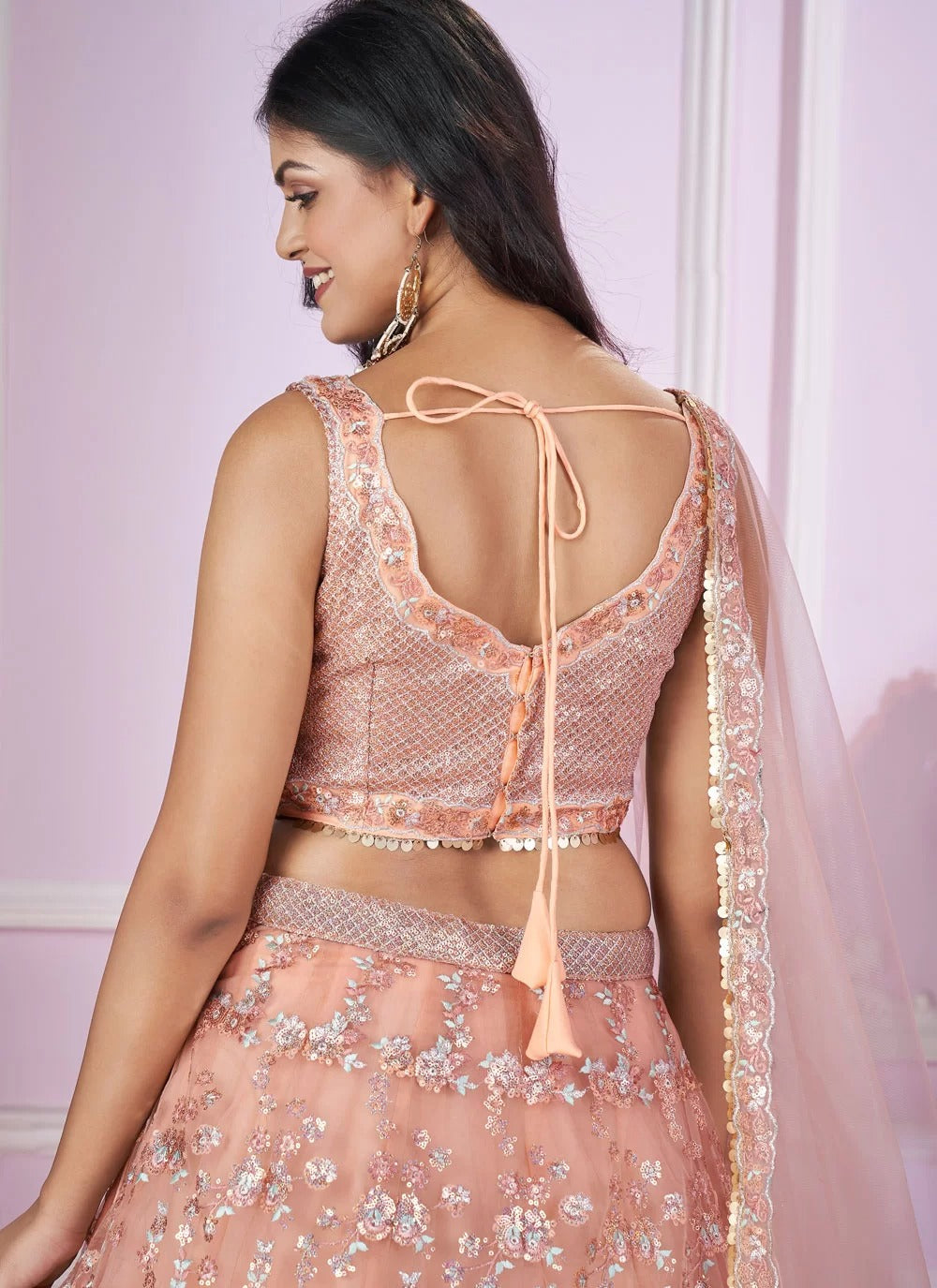 Woman wearing a pink embroidered traditional outfit with a light pink background