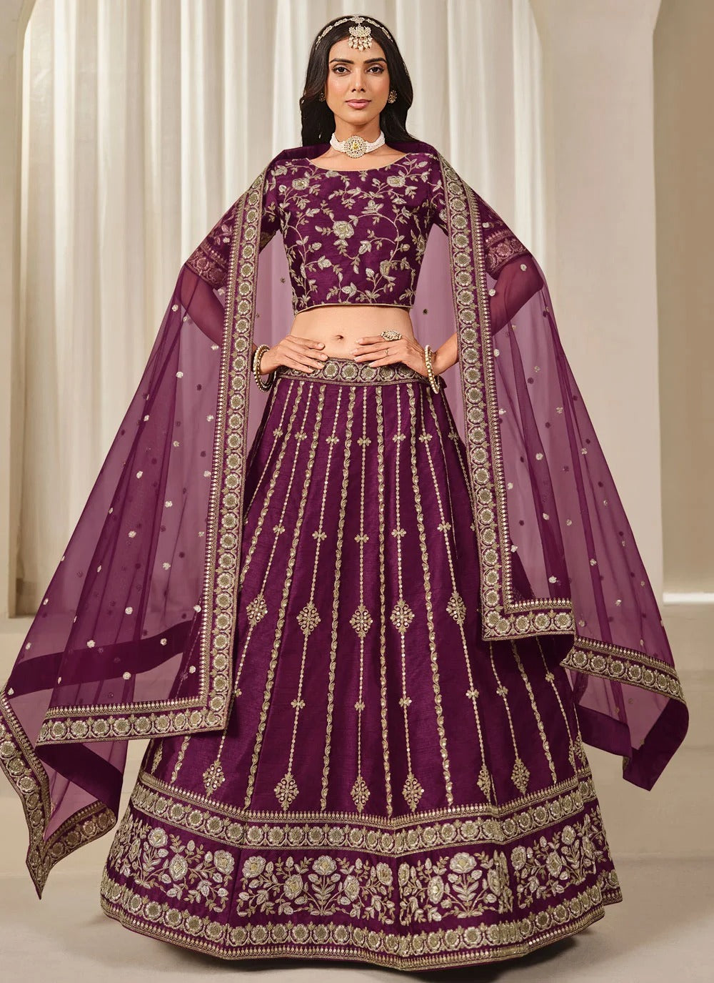Woman wearing a traditional purple embroidered outfit with a matching dupatta.