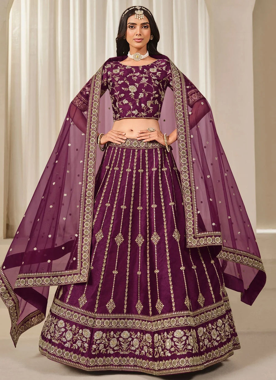 Woman wearing a traditional purple embroidered outfit with a matching dupatta.