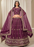 Woman wearing a traditional purple embroidered outfit with a matching dupatta.