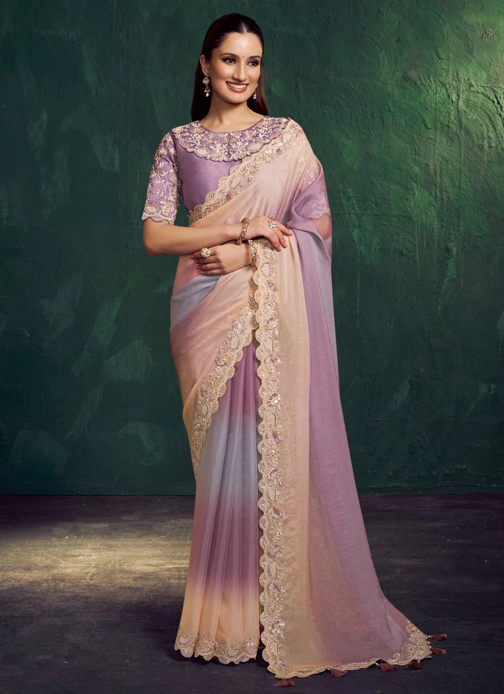Woman wearing a pink and purple saree with a green background