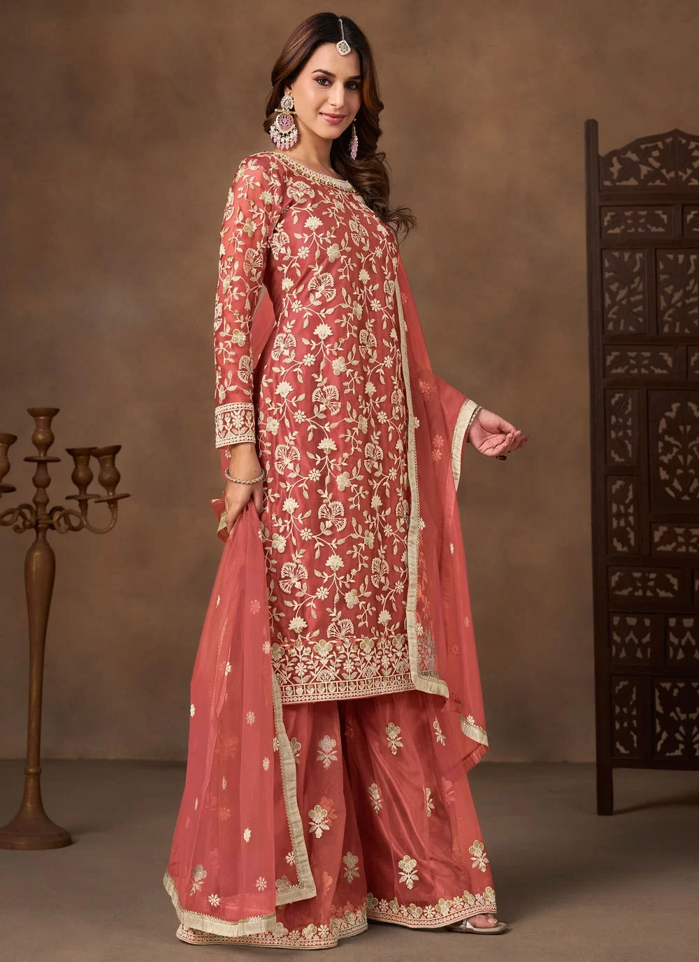 Woman wearing a traditional pink embroidered outfit with a brown background