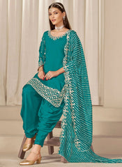 Woman wearing a teal traditional outfit with a matching dupatta against a neutral background