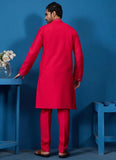 Man wearing a bright red kurta against a blue background