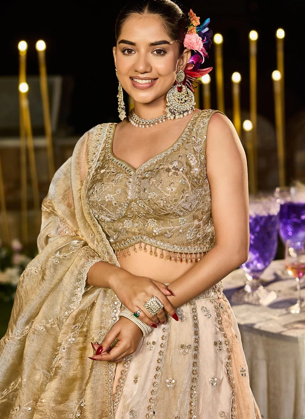 Woman in traditional embroidered outfit with jewelry, standing in a decorated indoor setting.