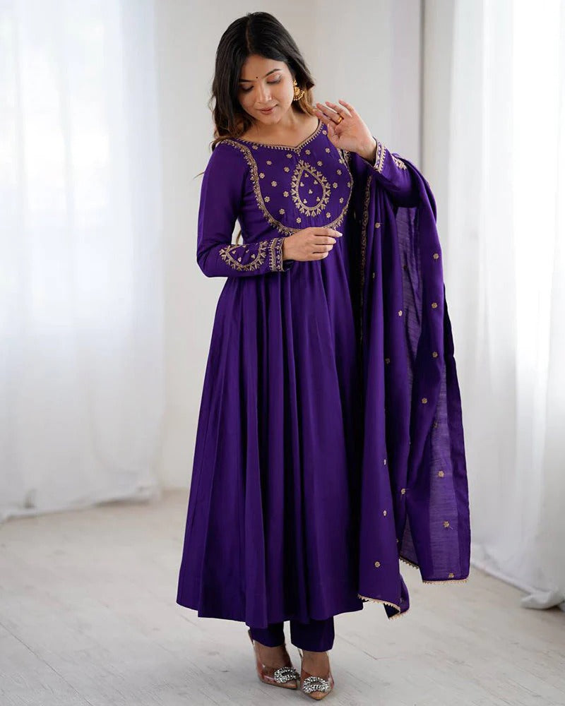 Woman wearing a purple traditional outfit with gold embroidery in a minimalistic setting
