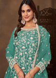 Woman wearing a teal embroidered traditional outfit with a blurred background