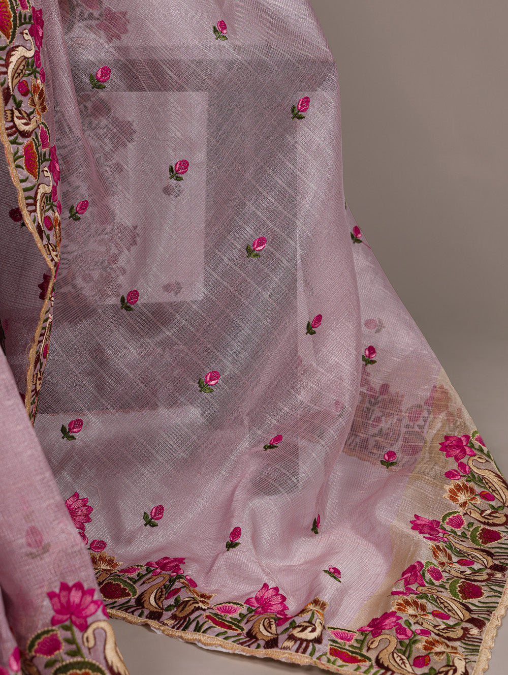 Pink embroidered fabric with floral patterns on a plain background