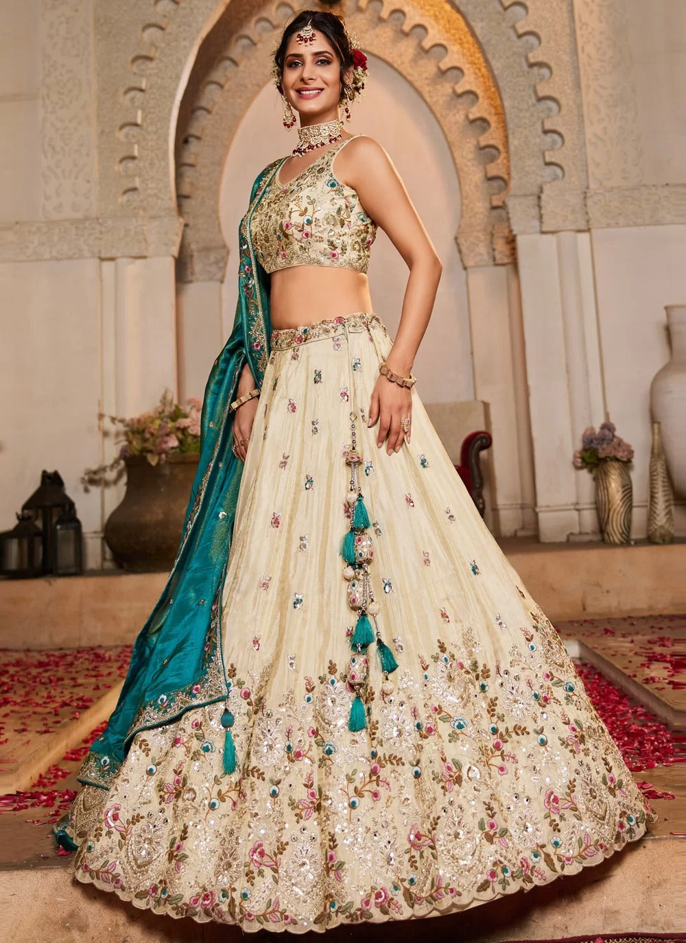Woman in a traditional outfit with a blue dupatta in an ornate indoor setting