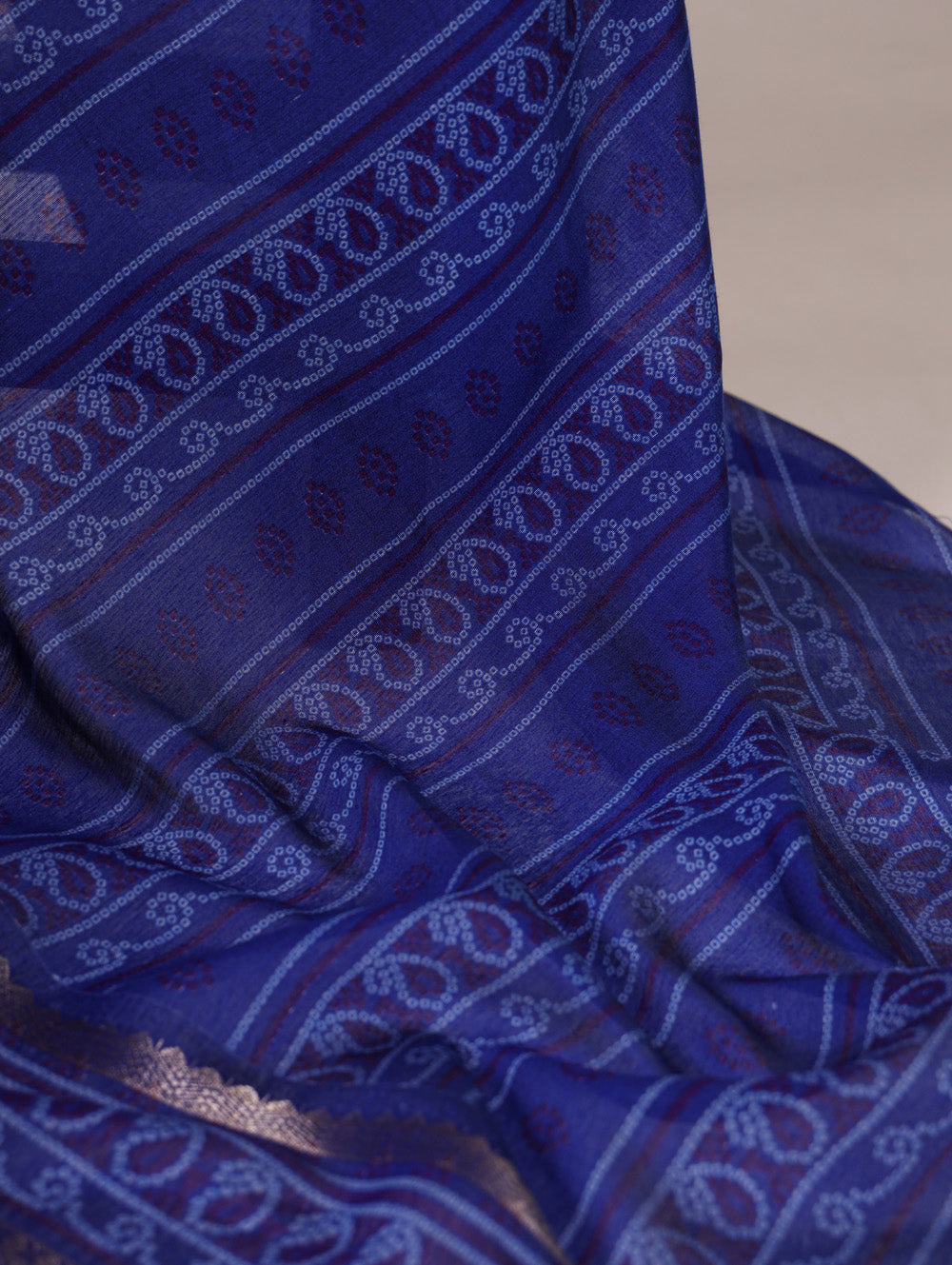 Blue fabric with white patterns, possibly a sari or scarf, on a neutral background.