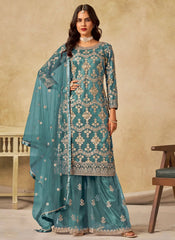 Woman wearing a teal embroidered traditional outfit with a beige background