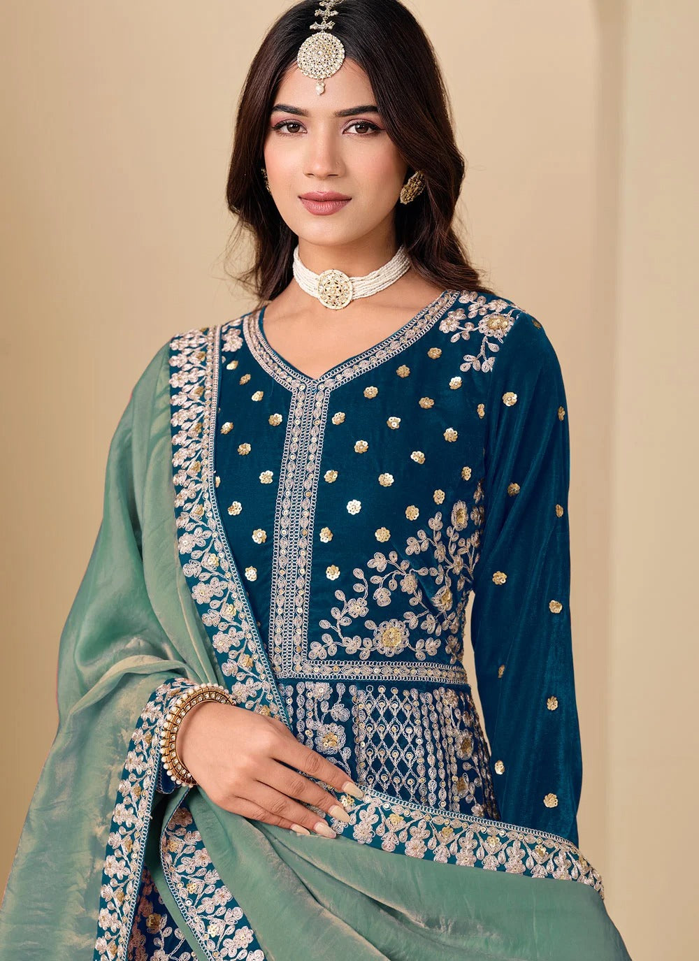 Woman wearing a traditional embroidered outfit with a plain background