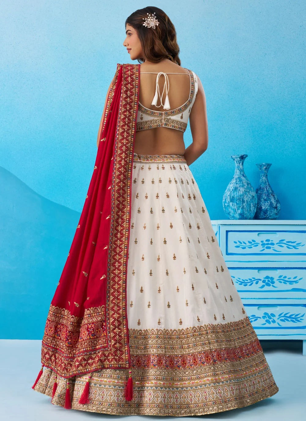 White Chinnon Silk semi-stitched lehenga set with embroidered blouse, matching dupatta and designer tassels for wedding wear.