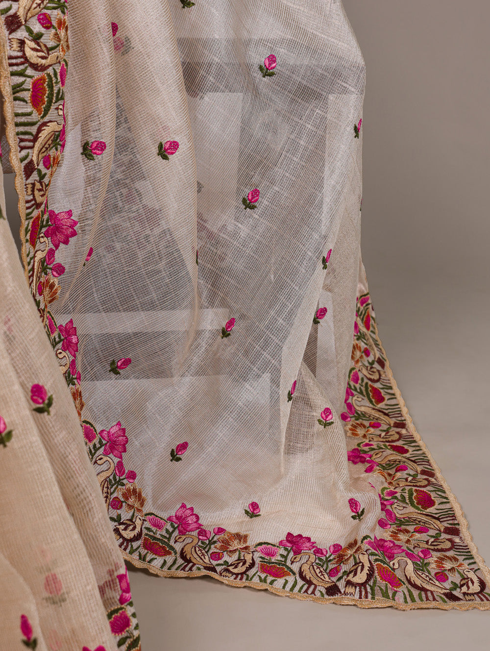 White embroidered fabric with pink flowers and colorful border on a neutral background